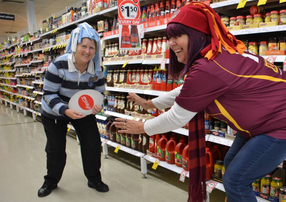 BATTLE ON: Blues supporter Debbie Mepham confronts maroons fan Leanne Parker in the aisles of Coles as the supermarket supports a fundraiser for kids in hospitals.