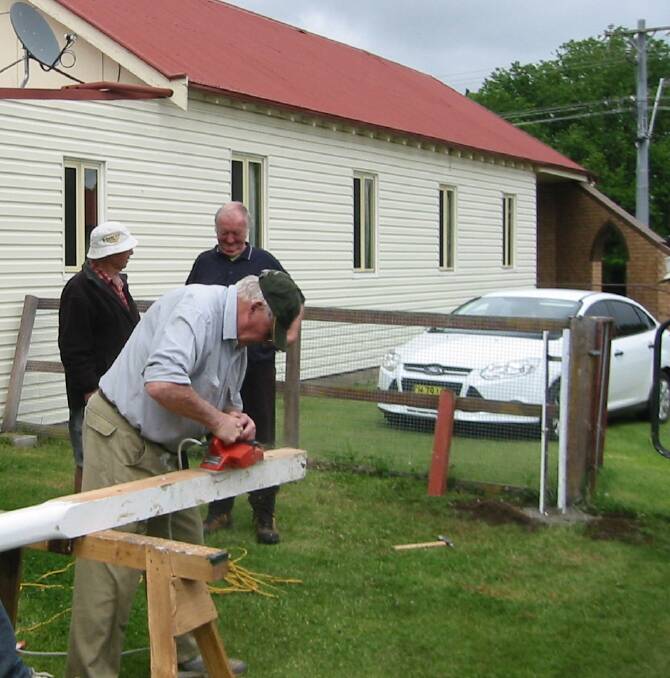 Men from the Men's Shed prepare the pole to hold the weather-measureing equipment.