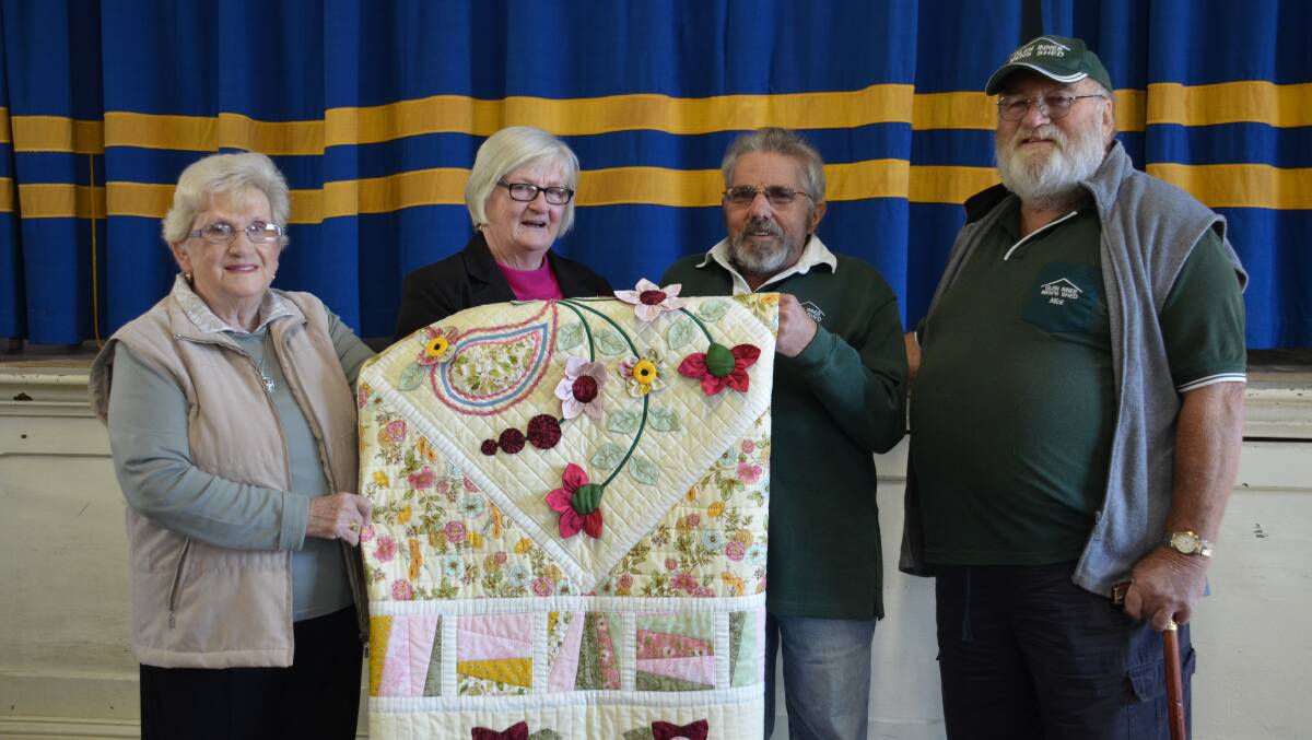 Val King and Kay Gall from Uniting Church Quilting and Craft Group hand over the quilt to Paul Raper and Mick Gall from Glen Innes Men’s Shed. 