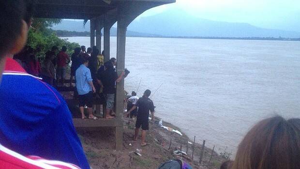 Locals watch as debris from the plane washes ashore on the banks of the Mekong River. Photo: Nana Nnpv/Facebook .