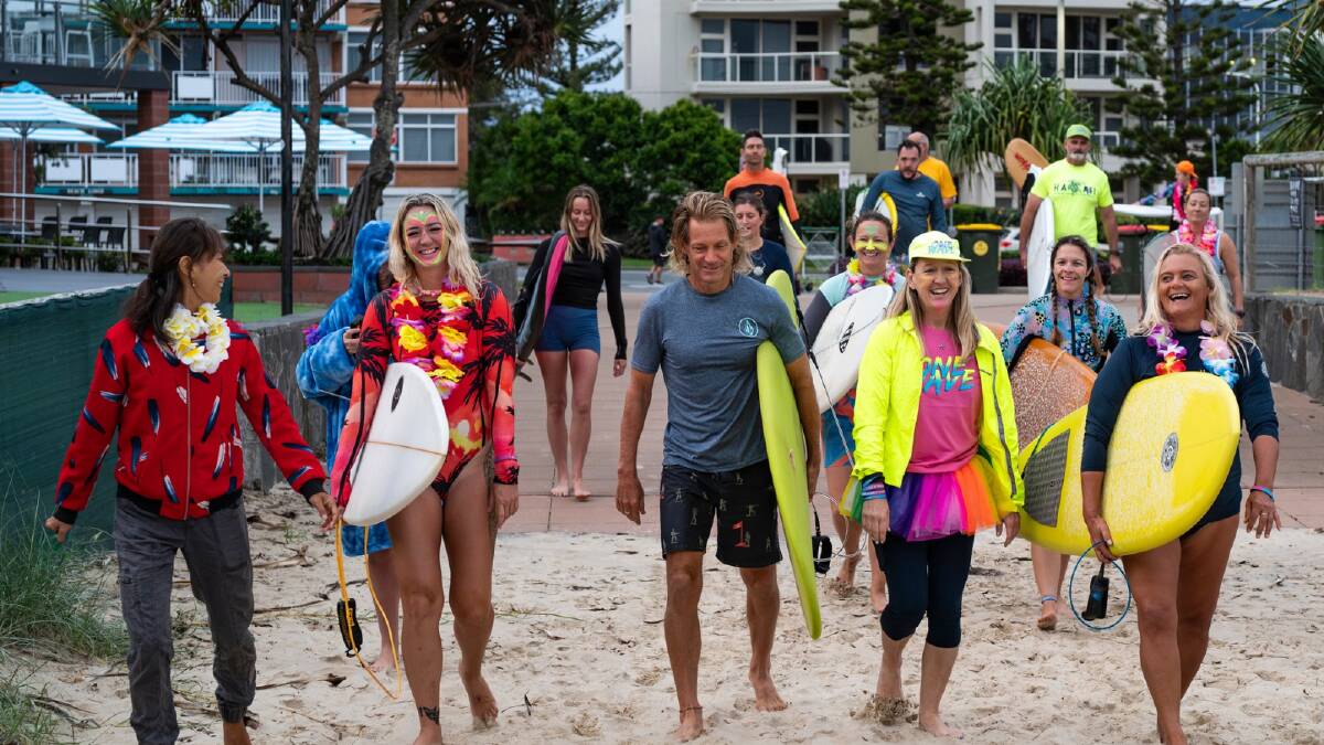 Cherisa Pearce in a multi-colour tutu with members of the OneWave Greenmount Beach surfers. Picture supplied