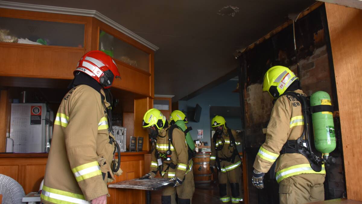 Glen Innes fire teams help suppress lingering embers at the Great Central pub this morning.