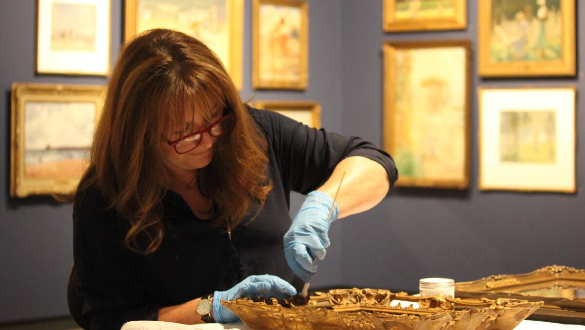 PRESERVATION: Paper conservator Jennifer Taylor cleans one of hundreds of original frames on the Howard Hinton collected works at New England Regional Art Museum. 