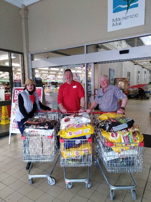 RSPCA' volunteer Brigitte Burridge, Coles manager Anthony Veldhuizen, and "R U Aware We Care" drought fundraiser David Donnelly, with trolleys of dog food to take out to farmers.
