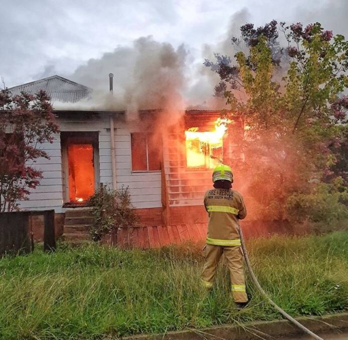UNDER CONTROL: A member of the Glen Innes brigade tackles the house fire head on.